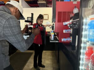 Cameraman records a worker operating a red soda fountain at a fast-food drink counter.